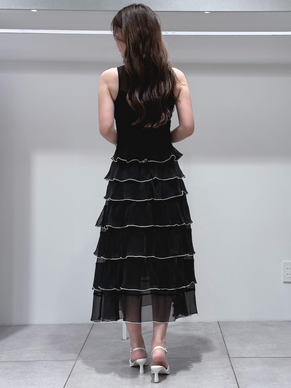 ホワイト系のハンドバッグ、ブラック系のワンピース、ホワイト系のパンプスを着用したレディースの夏コーディネートの4枚目の写真