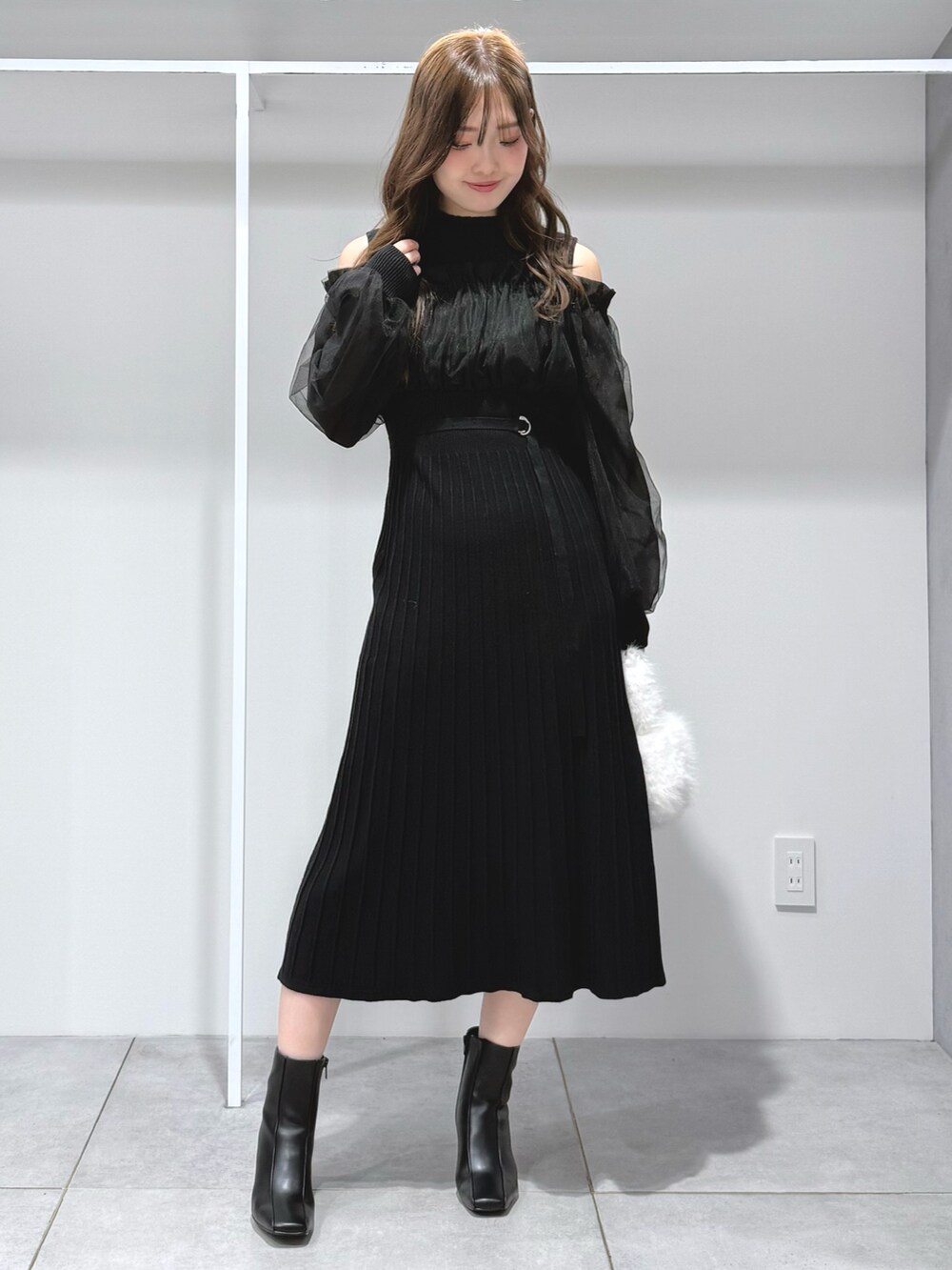 ブラック系のワンピース、ホワイト系のハンドバッグ、ブラック系のブーツを着用したレディースの秋コーディネートの7枚目の写真