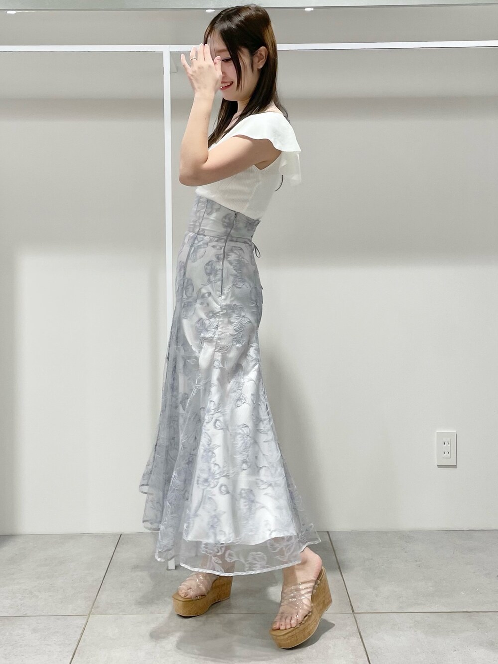 ホワイト系のニット/セーター、ブルー系のスカート、その他のサンダルを着用したレディースの春コーディネートの2枚目の写真