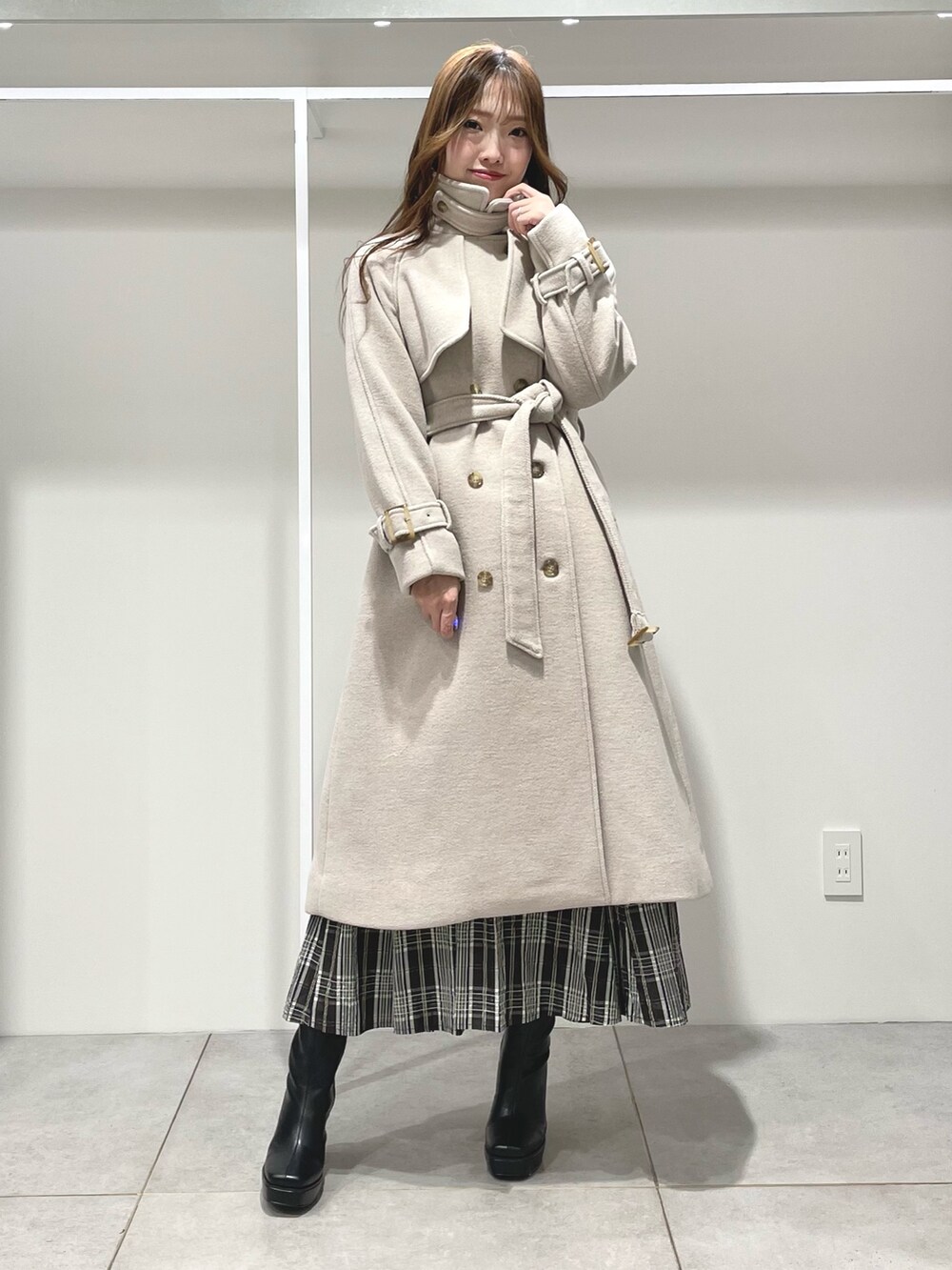 ブラック系のスカート、ブラック系のブーツ、ホワイト系のニット/セーターを着用したレディースの秋コーディネートの2枚目の写真