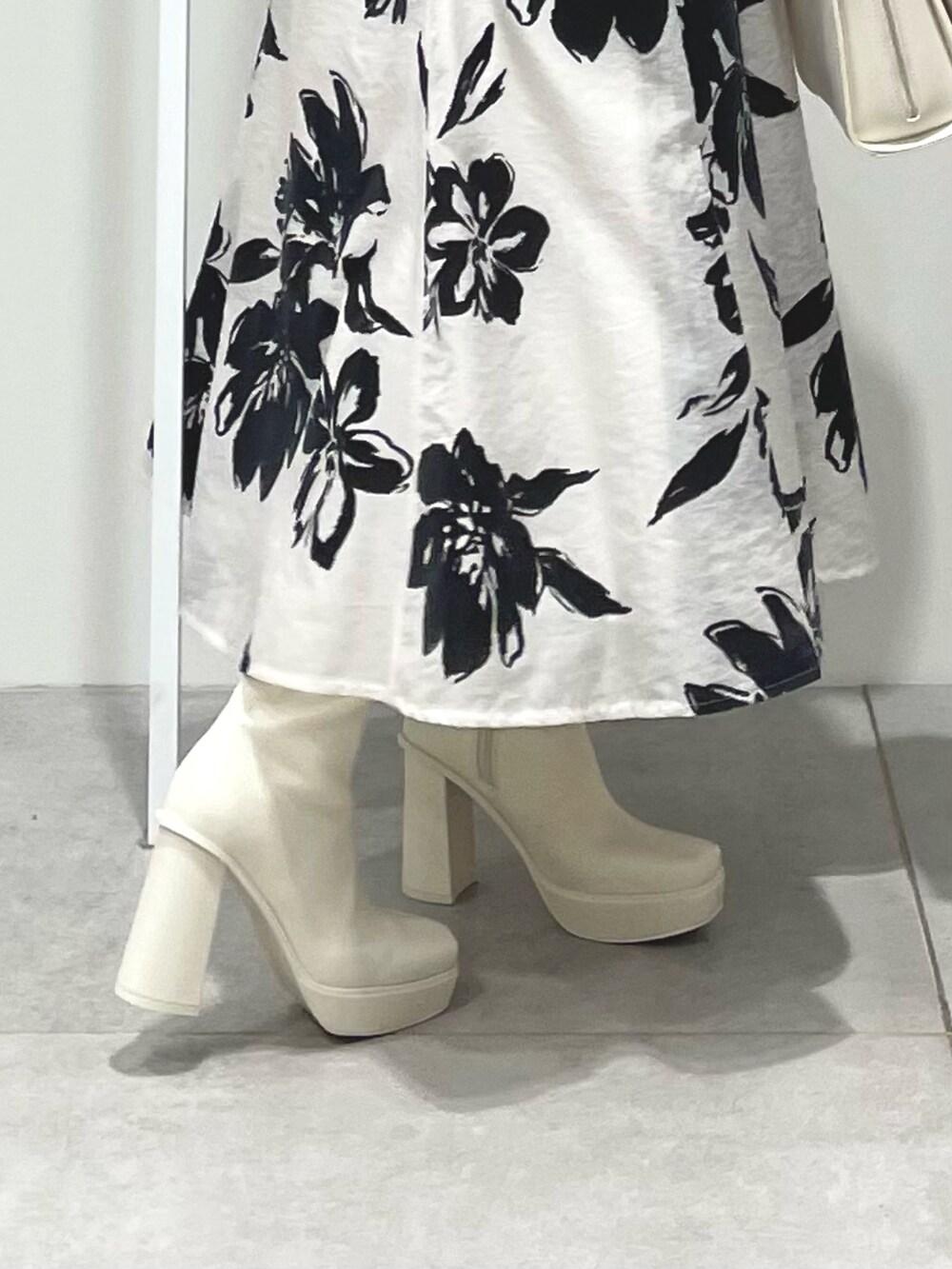 ホワイト系のスカート、ホワイト系のチェスターコート、ベージュ系のカーディガン/ボレロを着用したレディースの秋コーディネートの8枚目の写真