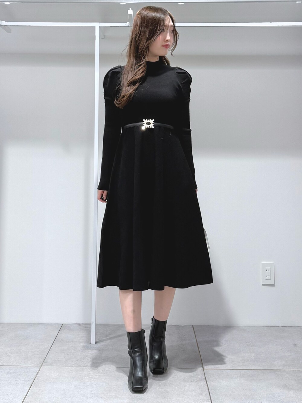 ホワイト系のハンドバッグ、ブラック系のブーツ、ブラック系のワンピースを着用したレディースの冬コーディネートの2枚目の写真