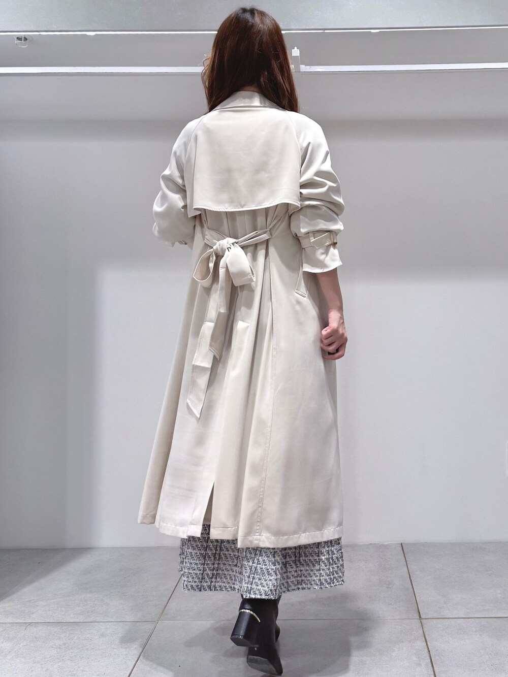 ホワイト系のトレンチコート、ブラック系のワンピース、ブラック系のブーツを着用したレディースの冬コーディネートの4枚目の写真