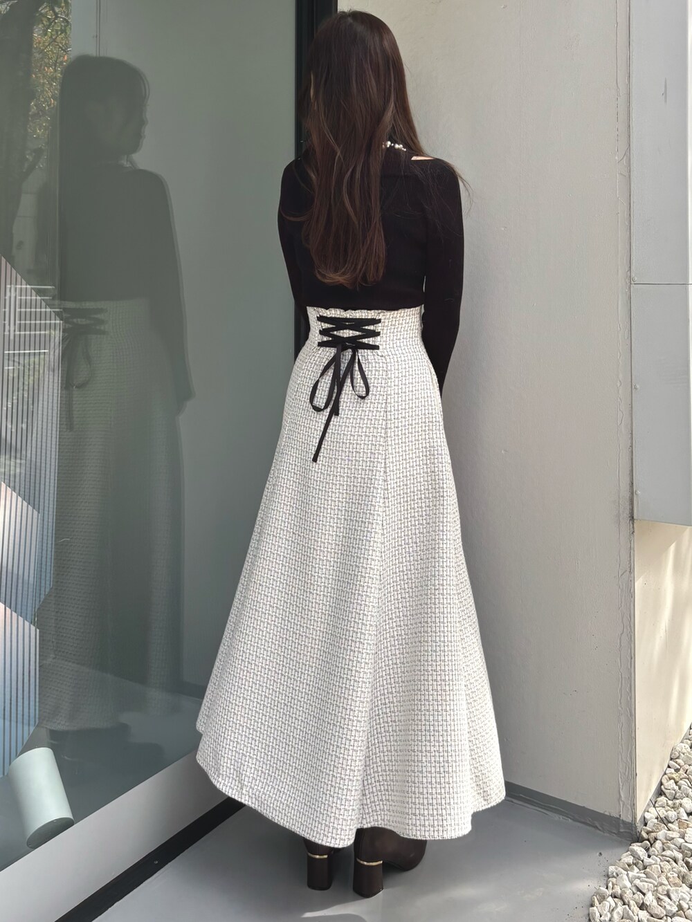 ブラック系のニット/セーター、レッド系のハンドバッグ、ホワイト系のスカートを着用したレディースの冬コーディネートの4枚目の写真