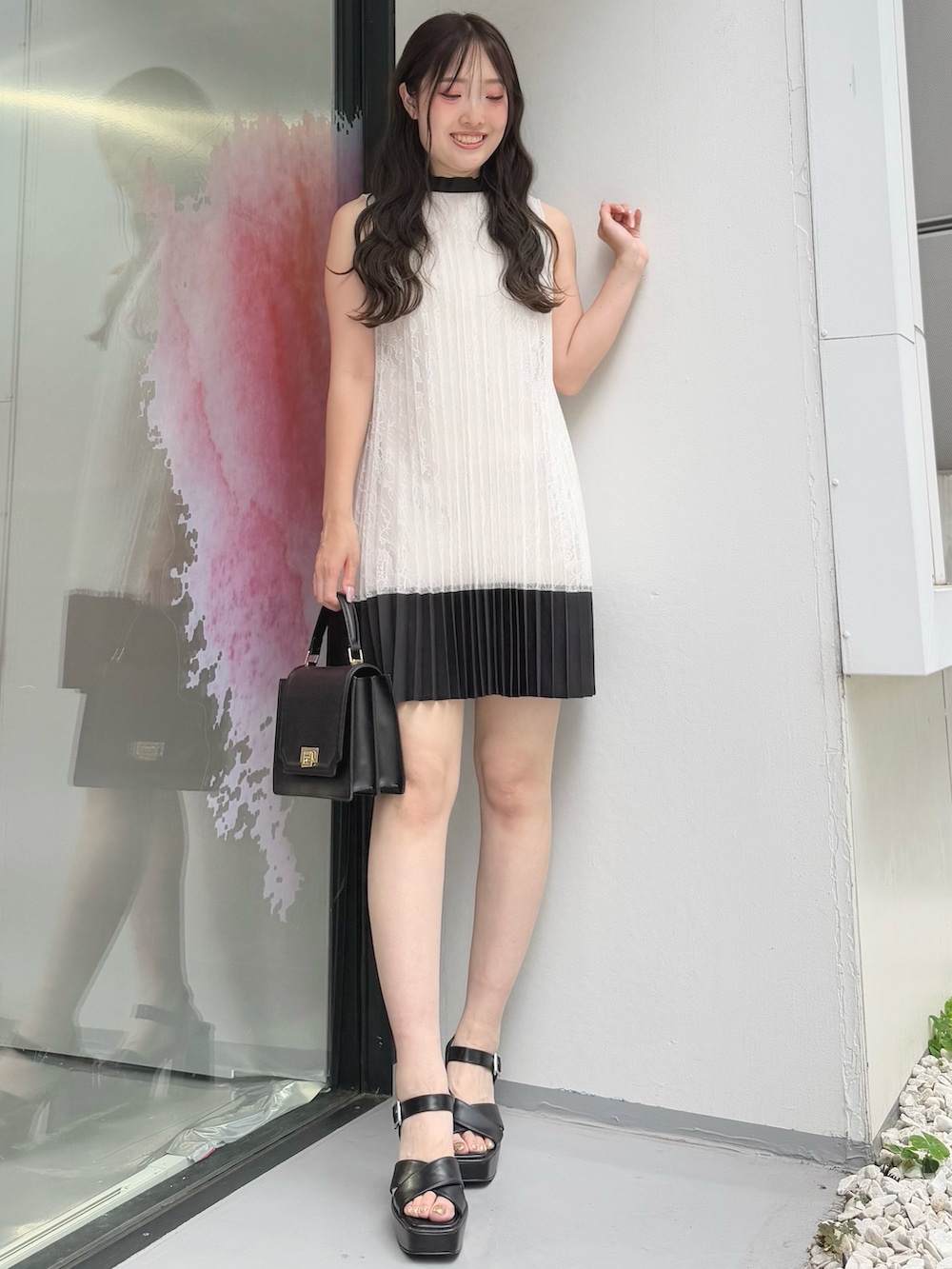 ホワイト系のワンピース、ブラック系のハンドバッグ、ブラック系のサンダルを着用したレディースの夏コーディネートの2枚目の写真