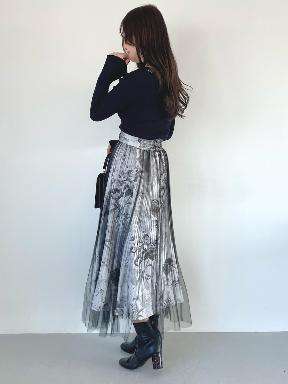 ブラック系のブーツ、ブラック系のスカート、ブラック系のハンドバッグを着用したレディースの春コーディネートの4枚目の写真