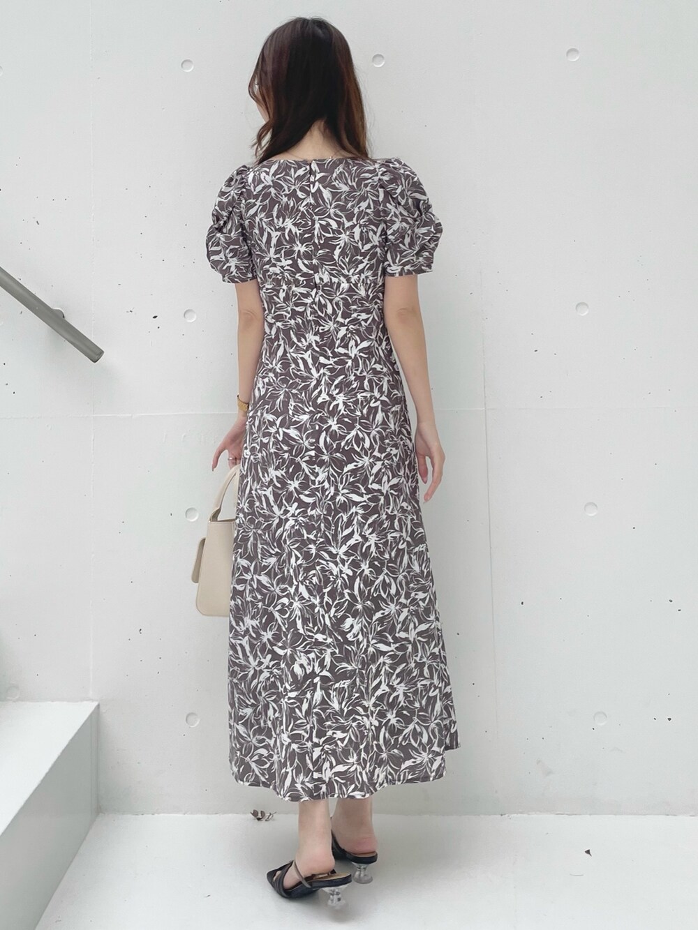 グレー系のワンピース、ブラック系のサンダル、ホワイト系のハンドバッグを着用したレディースの春コーディネートの3枚目の写真