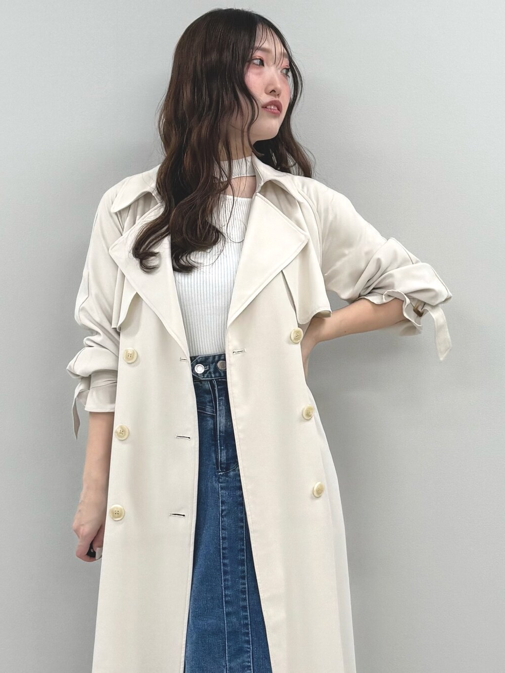 ブルー系のスカート、ホワイト系のニット/セーター、ホワイト系のトレンチコートを着用したレディースの春コーディネートの6枚目の写真