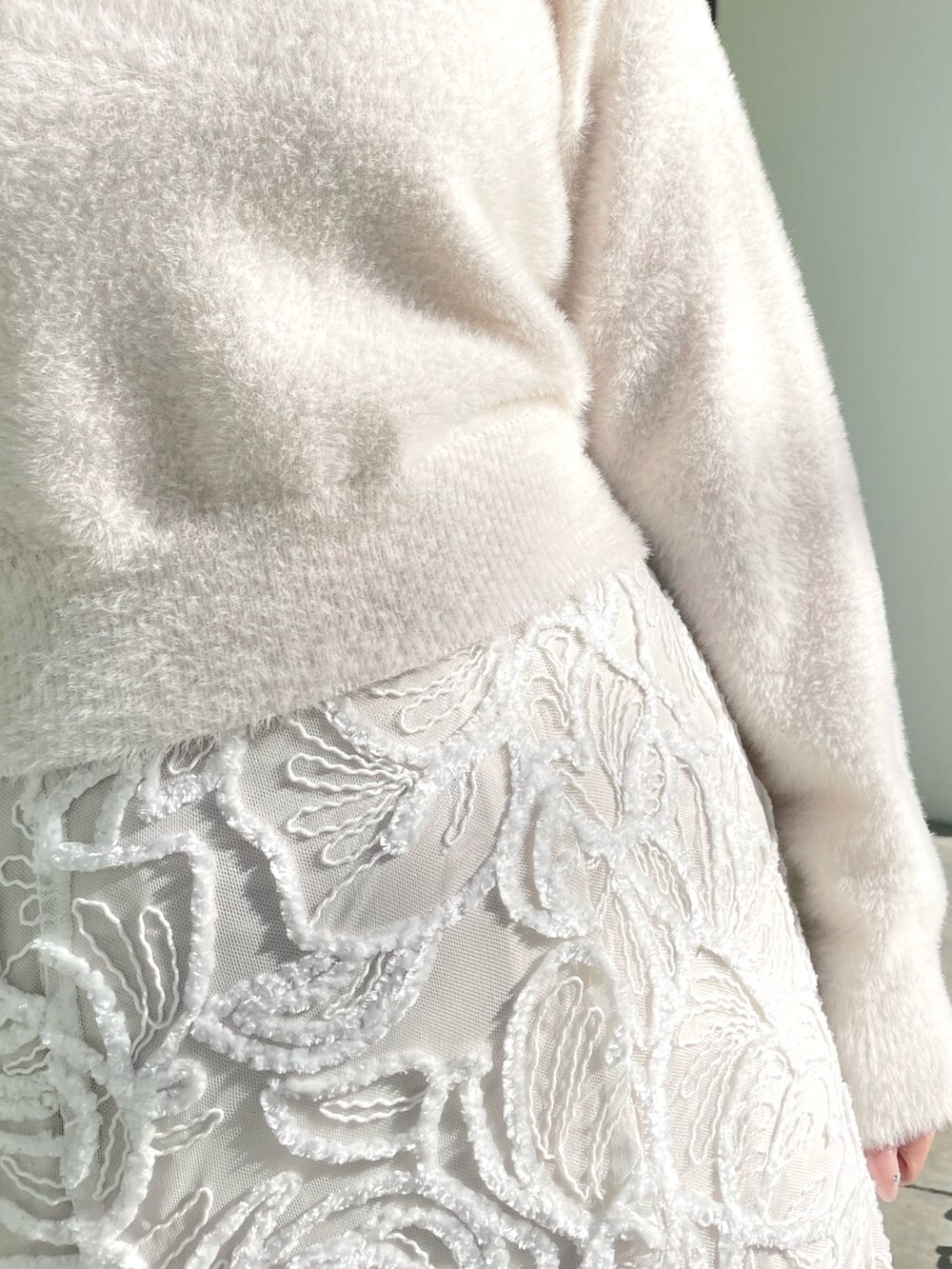 ホワイト系のダウンジャケット/コート、ホワイト系のニット/セーター、ホワイト系のスカートを着用したレディースの冬コーディネートの9枚目の写真