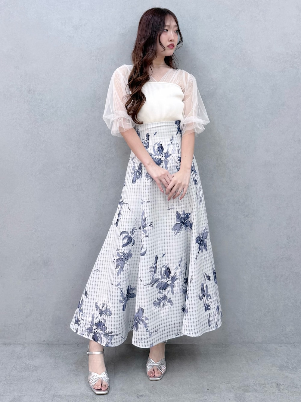 ホワイト系のニット/セーター、シルバー系のサンダル、ブルー系のスカートを着用したレディースの春コーディネートの2枚目の写真