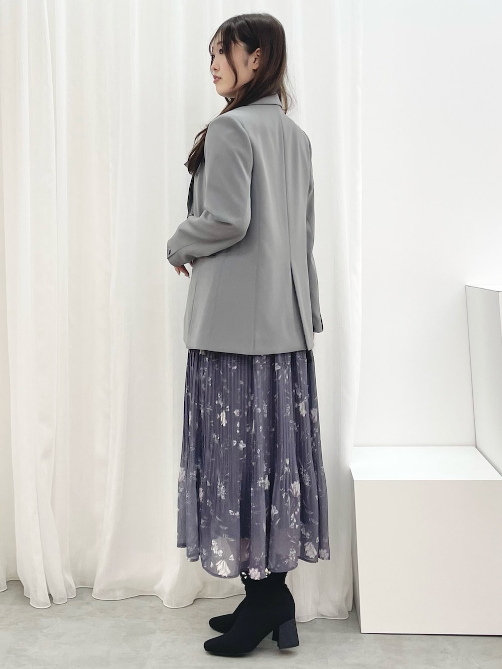 グレー系のワンピース、ブラック系のブーツ、グレー系のテーラードジャケットを着用したレディースの秋コーディネートの2枚目の写真