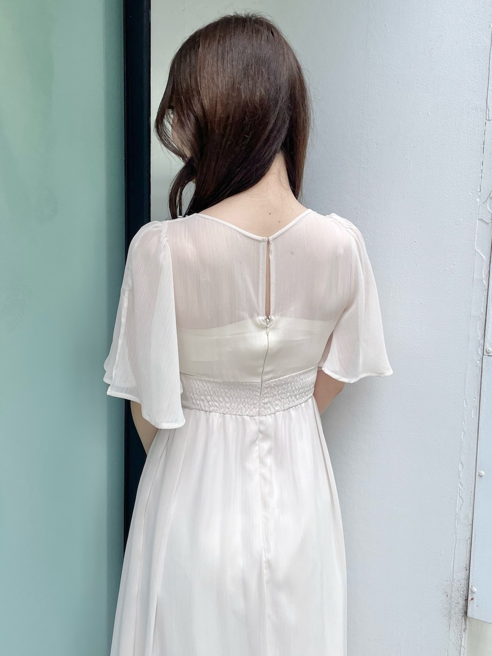 ホワイト系のワンピース、シルバー系のハンドバッグ、シルバー系のサンダルを着用したレディースの夏コーディネートの7枚目の写真
