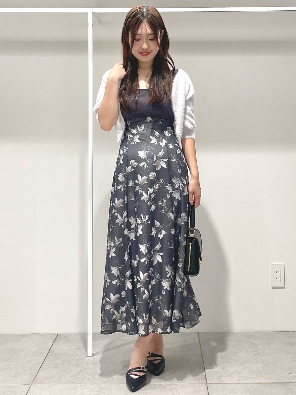 ブラック系のパンプス、ブラック系のショルダーバッグ、グレー系のワンピースを着用したレディースの夏コーディネートの2枚目の写真