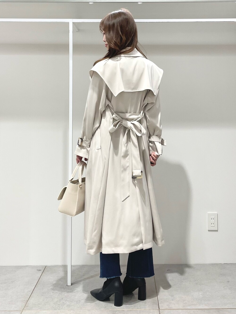 ホワイト系のハンドバッグ、ブラック系のブーツ、ブルー系のニット/セーターを着用したレディースの冬コーディネートの2枚目の写真