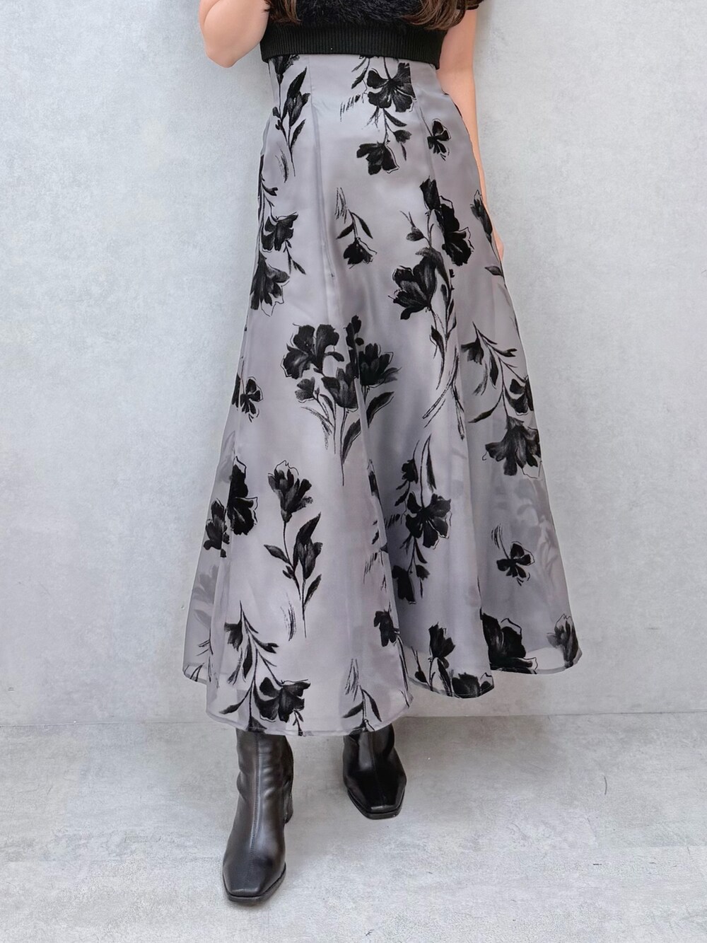 ブラック系のスカート、ブラック系のニット/セーター、ブラック系のブーツを着用したレディースの夏コーディネートの5枚目の写真