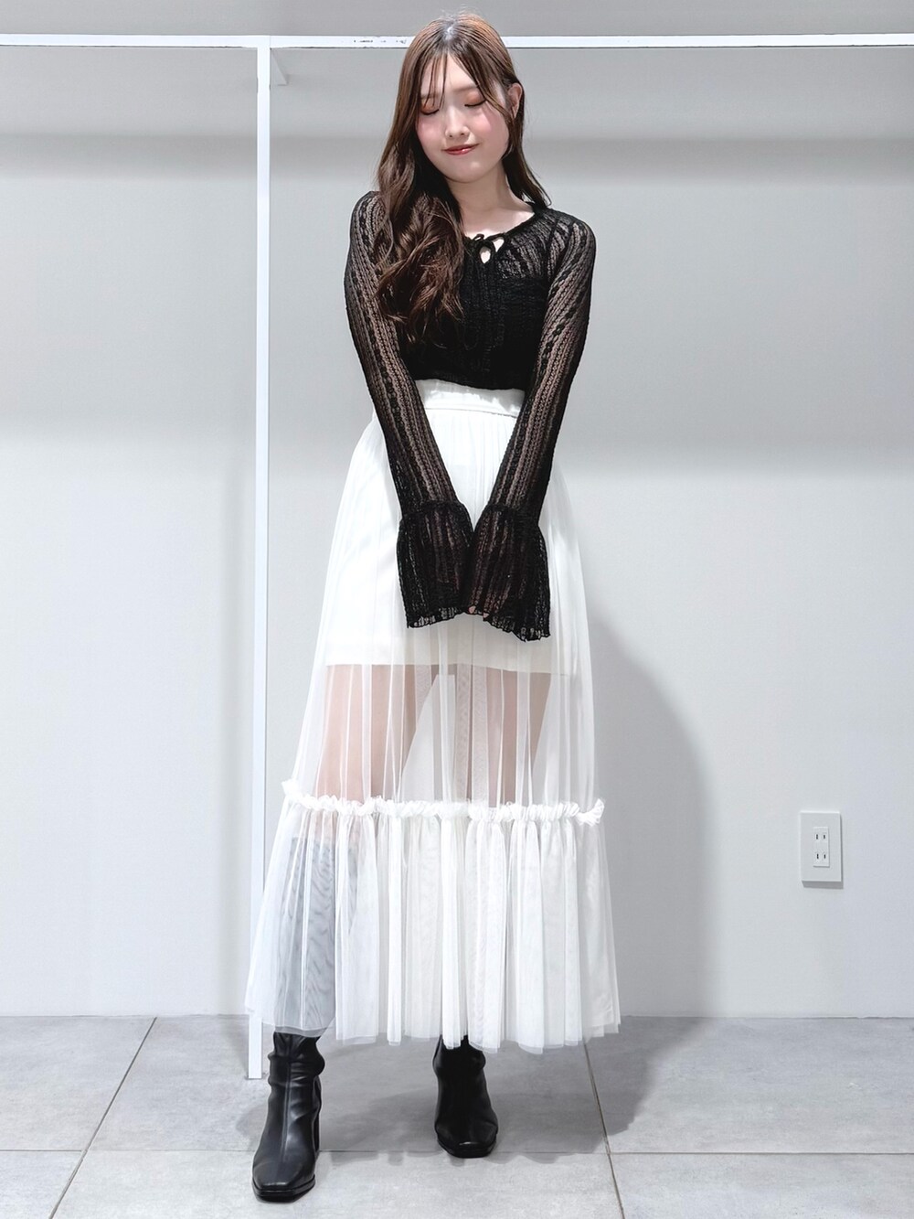 ブラック系のブーツ、ホワイト系のスカート、ブラック系のTシャツ/カットソーを着用したレディースの秋コーディネートの2枚目の写真