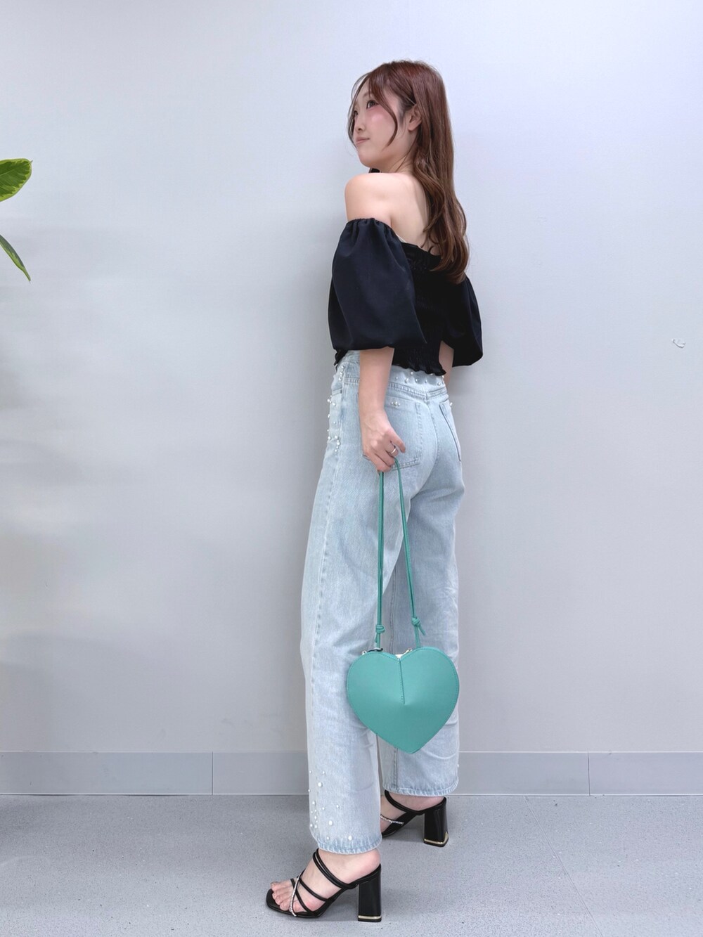 ブルー系のデニムパンツ、グリーン系のショルダーバッグ、ブラック系のサンダルを着用したレディースの夏コーディネートの2枚目の写真