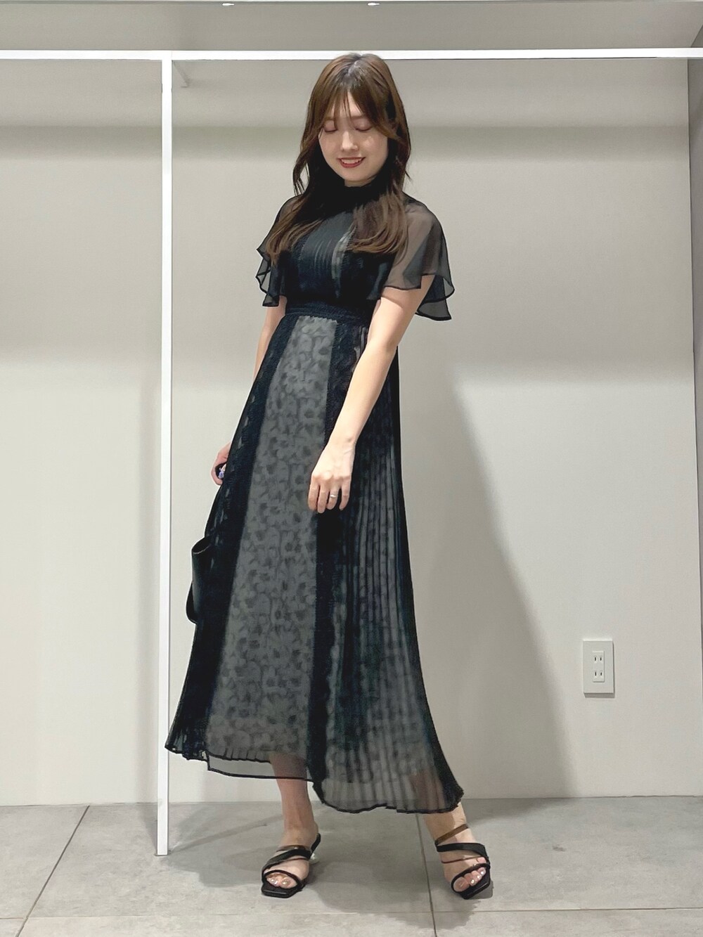 ブラック系のワンピース、ブラック系のトートバッグ、ブラック系のサンダルを着用したレディースの夏コーディネートの3枚目の写真