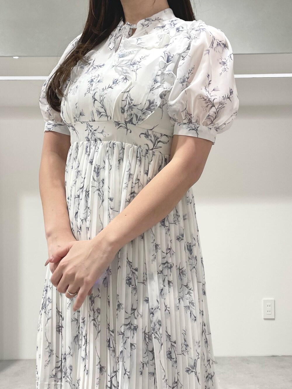 ホワイト系のトレンチコート、ホワイト系のワンピース、シルバー系のパンプスを着用したレディースの春コーディネートの6枚目の写真