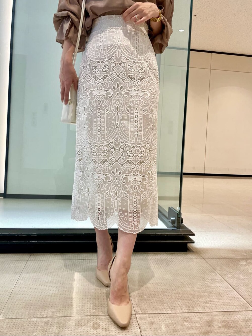 ピンク系のシャツ/ブラウス、ホワイト系のスカート、ベージュ系のパンプスを着用したレディースの夏コーディネートの5枚目の写真