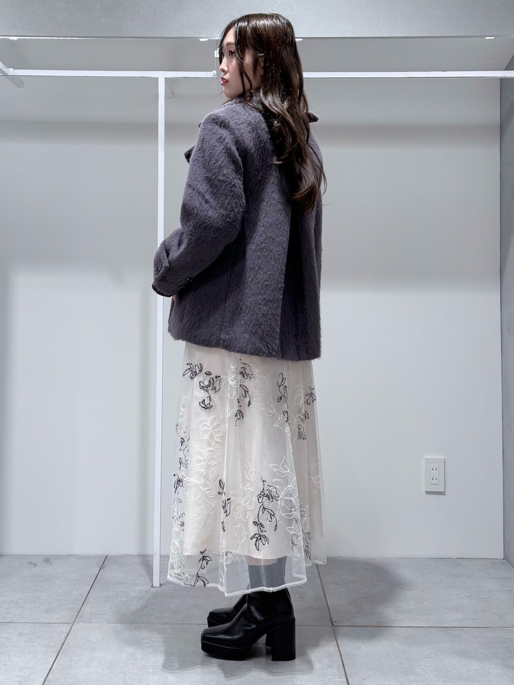 グレー系のその他アウター、グレー系のニット/セーター、ホワイト系のスカートを着用したレディースの冬コーディネートの3枚目の写真