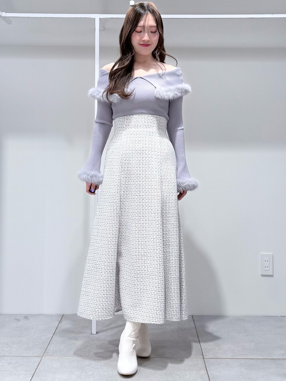 グレー系のニット/セーター、ホワイト系のスカート、ホワイト系のブーツを着用したレディースの冬コーディネートの3枚目の写真