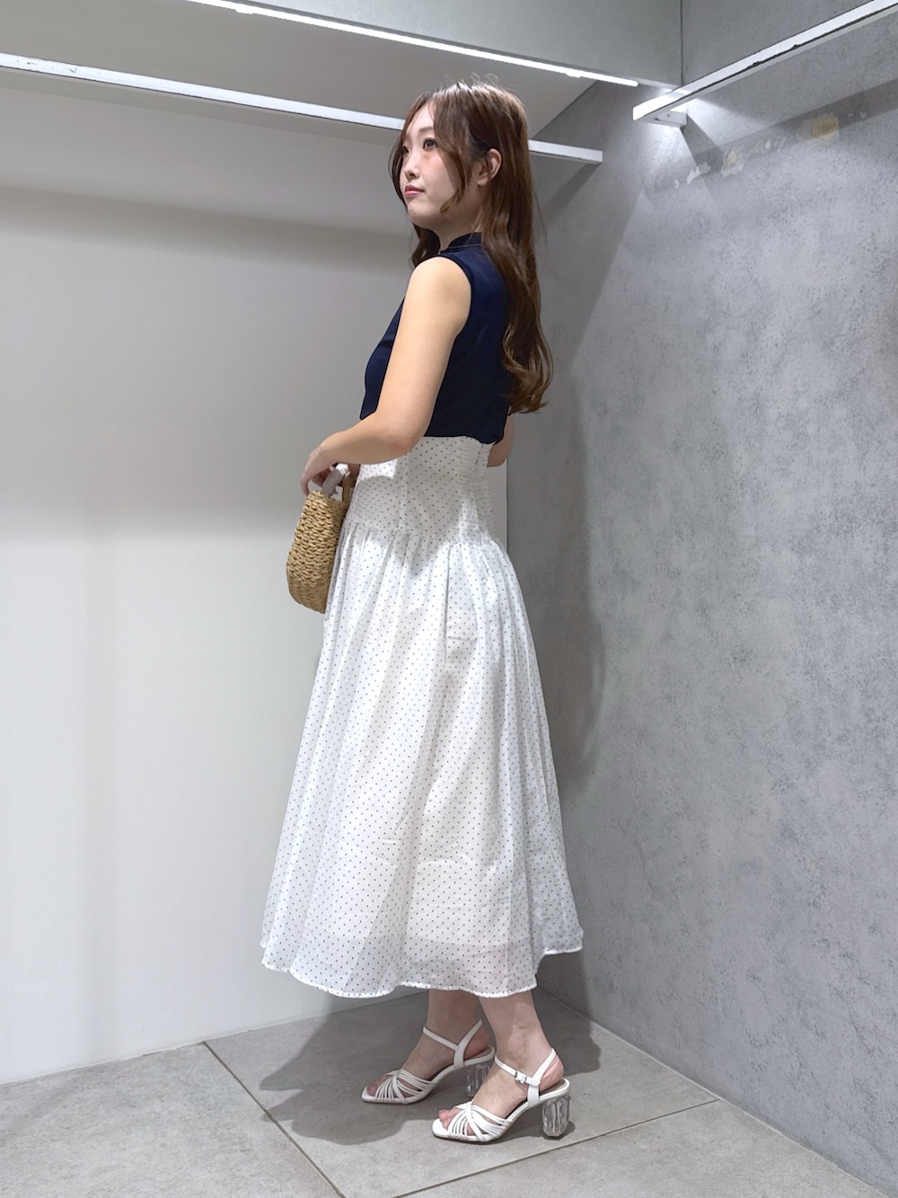 ホワイト系のワンピース、ベージュ系のハンドバッグ、ホワイト系のサンダルを着用したレディースの夏コーディネートの2枚目の写真