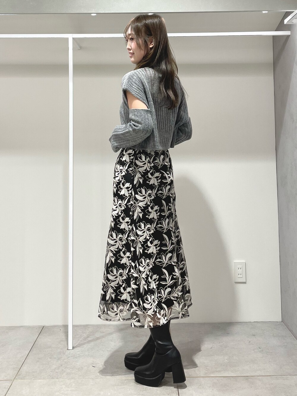 ブラック系のスカート、ブラック系のブーツ、グレー系のニット/セーターを着用したレディースの冬コーディネートの2枚目の写真