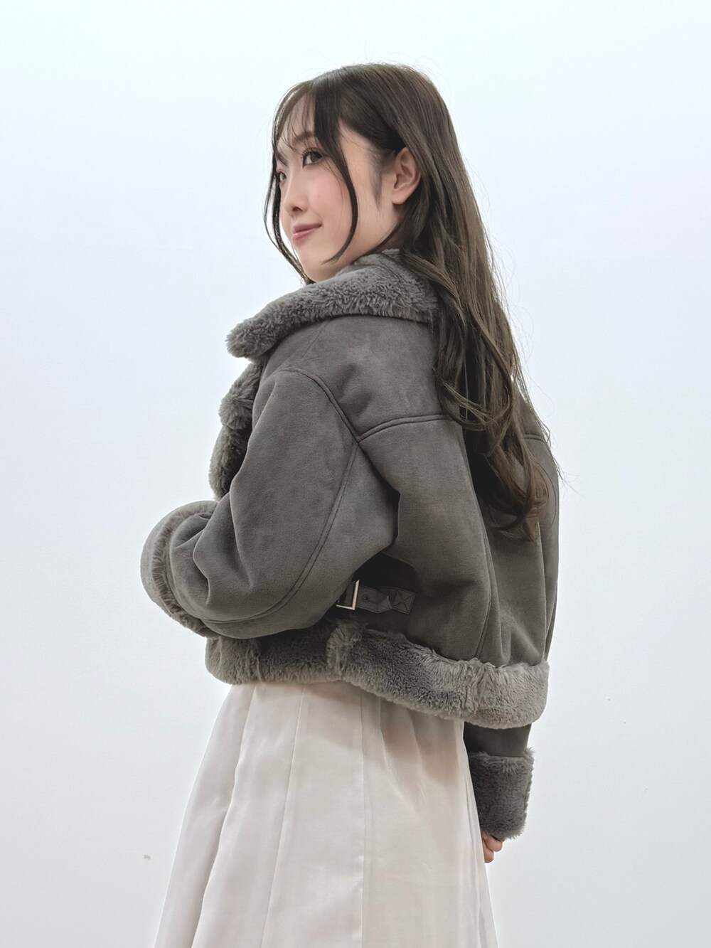 グレー系のスカート、ブラック系のブーツ、グレー系のムートンコートを着用したレディースの秋コーディネートの6枚目の写真