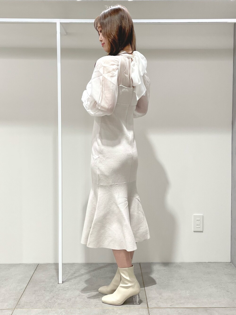 ホワイト系のチェスターコート、ピンク系のハンドバッグ、ホワイト系のワンピースを着用したレディースの冬コーディネートの7枚目の写真