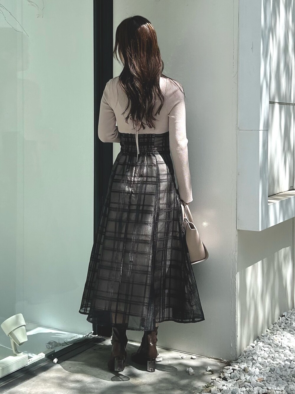 ピンク系のワンピース、ベージュ系のハンドバッグ、ホワイト系のライダースジャケットを着用したレディースの秋コーディネートの6枚目の写真