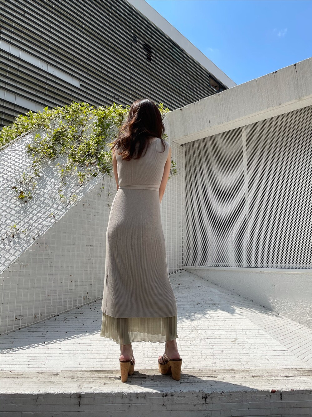 ホワイト系のハンドバッグ、ホワイト系のキャミソール、ベージュ系のサンダルを着用したレディースの夏コーディネートの3枚目の写真