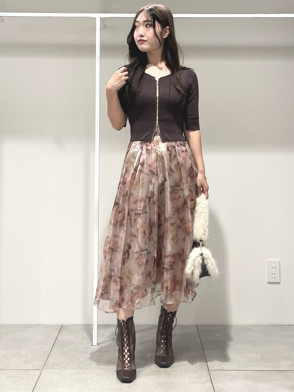 ブラウン系のニット/セーター、ピンク系のスカート、ブラウン系のブーツを着用したレディースの秋コーディネートの2枚目の写真