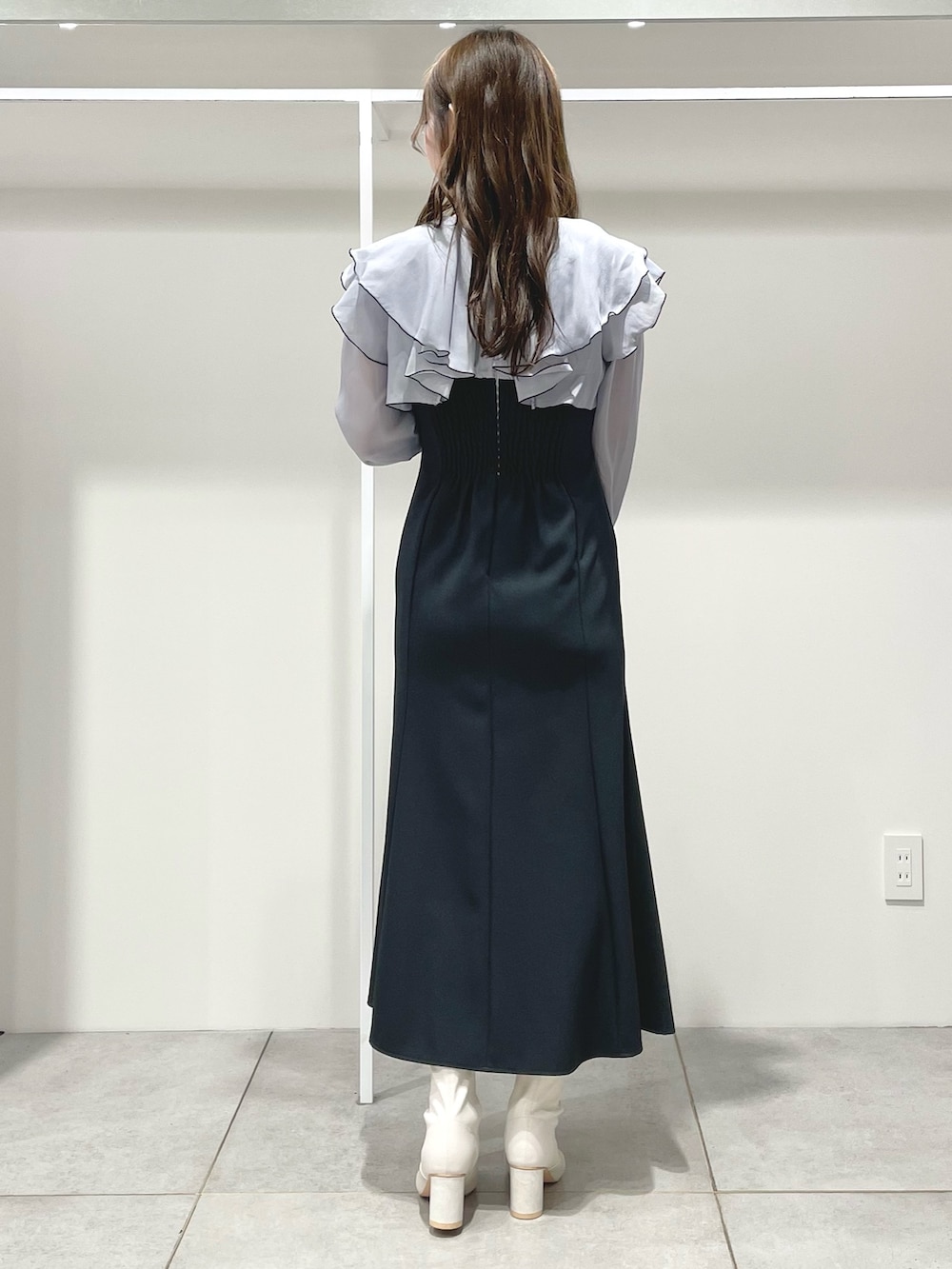 グレー系のワンピース、ホワイト系のブーツ、ホワイト系のハンドバッグを着用したレディースの冬コーディネートの4枚目の写真