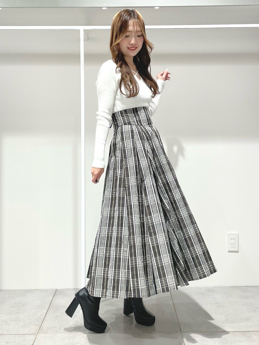 ブラック系のスカート、ブラック系のブーツ、ホワイト系のニット/セーターを着用したレディースの秋コーディネートの7枚目の写真