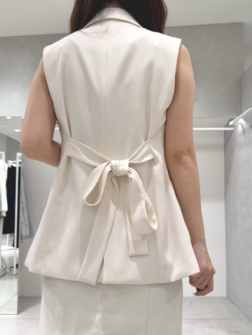 ホワイト系のワンピース、ベージュ系のサンダル、ホワイト系のベストを着用したレディースの春コーディネートの7枚目の写真