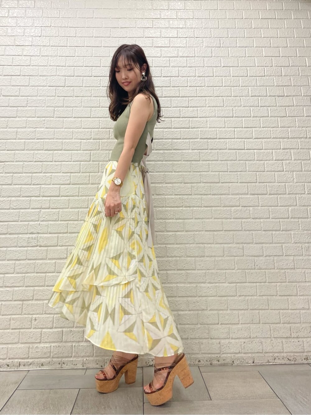 ベージュ系のサンダル、イエロー系のスカート、ベージュ系のニット/セーターを着用したレディースの夏コーディネートの2枚目の写真