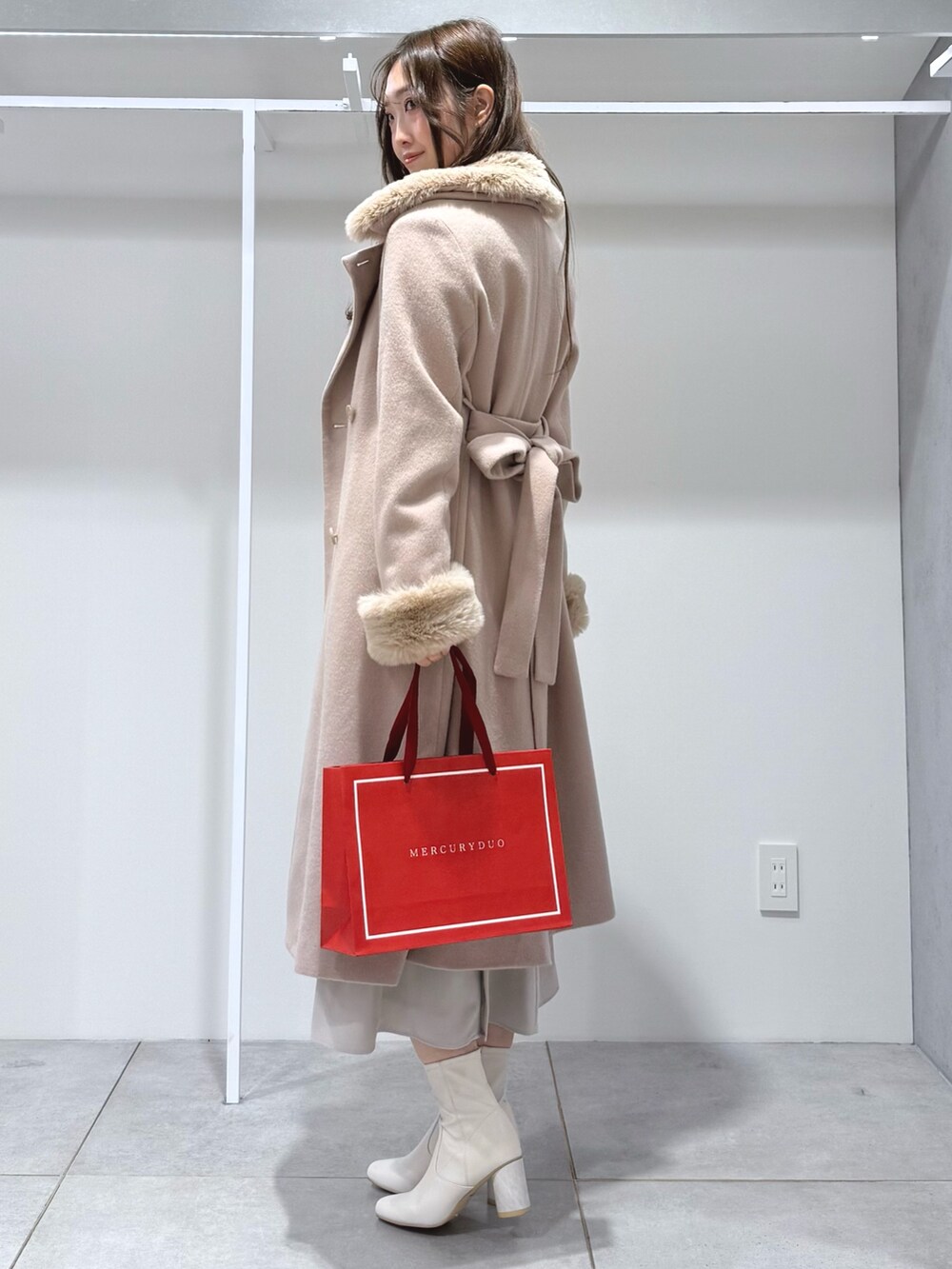 ベージュ系のその他アウター、ホワイト系のワンピース、ホワイト系のブーツを着用したレディースの冬コーディネートの2枚目の写真