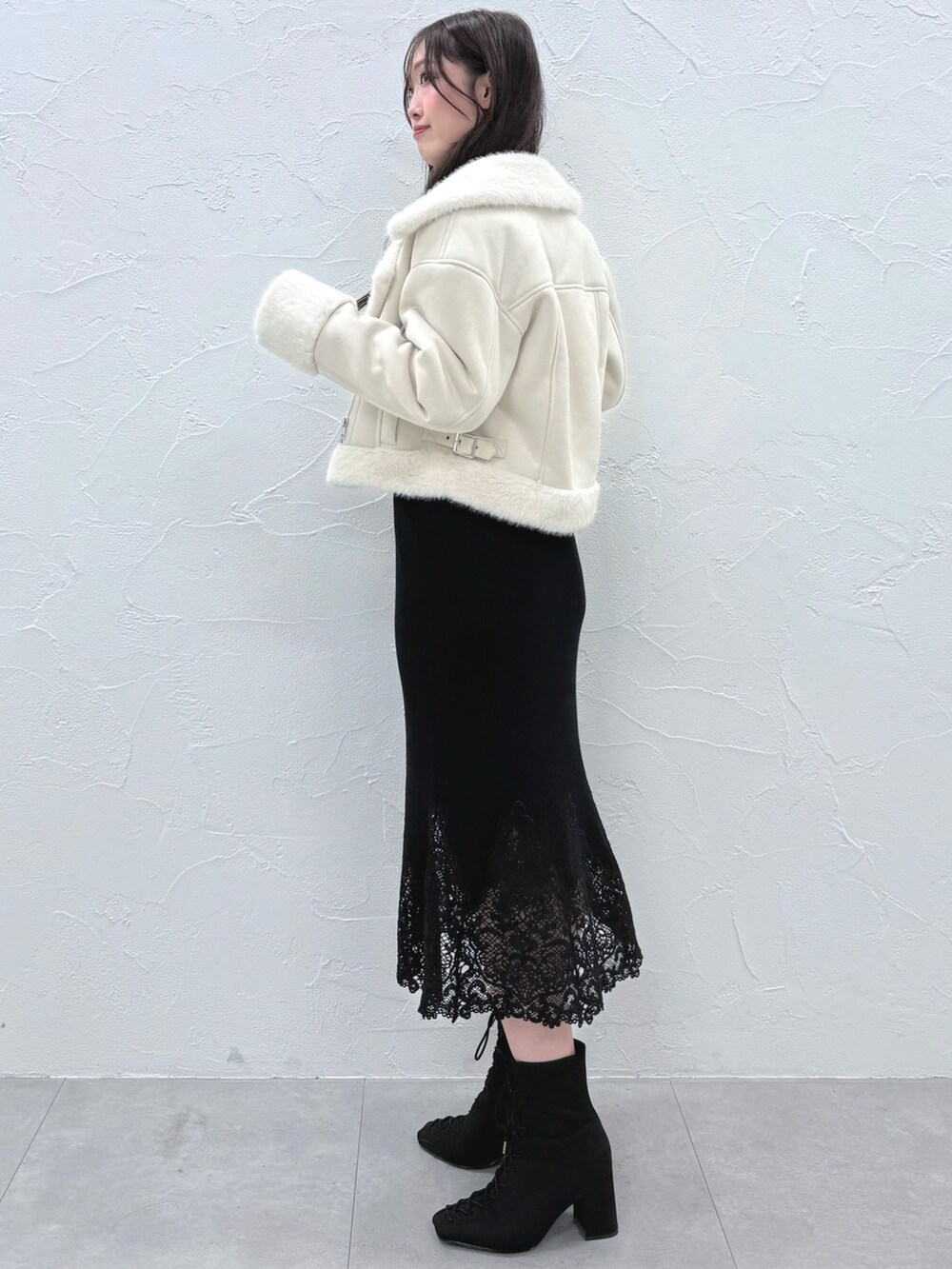 ブラック系のワンピース、ブラック系のブーツ、ホワイト系のムートンコートを着用したレディースの秋コーディネートの2枚目の写真