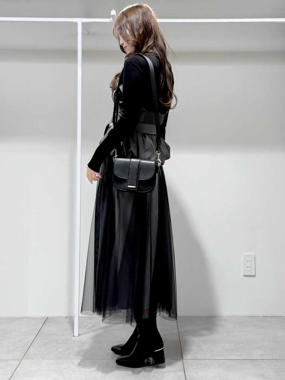 ブラック系のワンピース、ブラック系のブーツ、ブラック系のショルダーバッグを着用したレディースの冬コーディネートの3枚目の写真