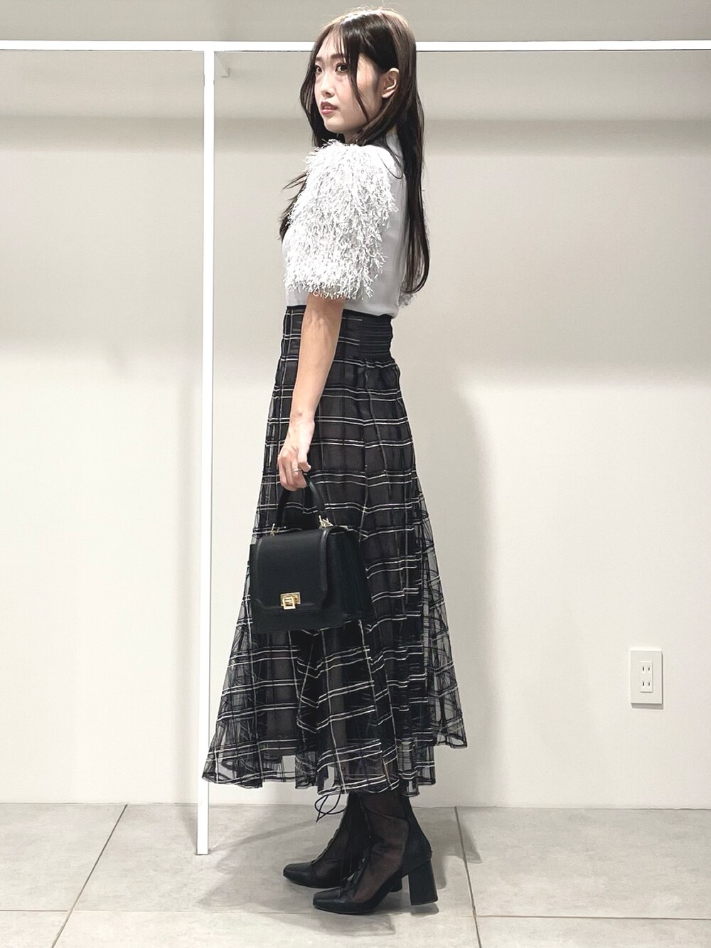 グレー系のニット/セーター、ブラック系のハンドバッグ、ブラック系のスカートを着用したレディースの秋コーディネートの3枚目の写真