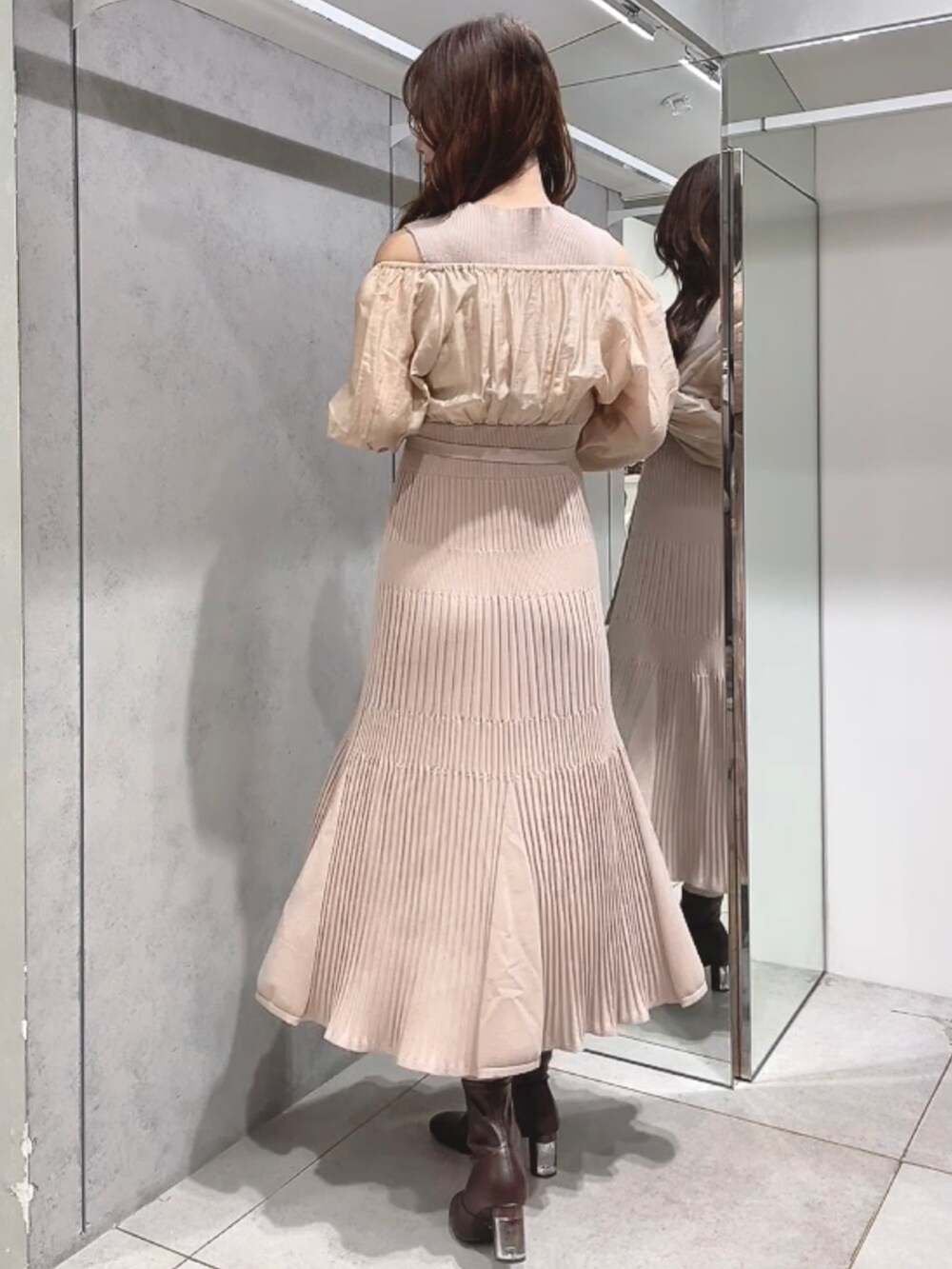 ブラウン系のチェスターコート、ベージュ系のワンピース、ブラウン系のブーツを着用したレディースの秋コーディネートの5枚目の写真