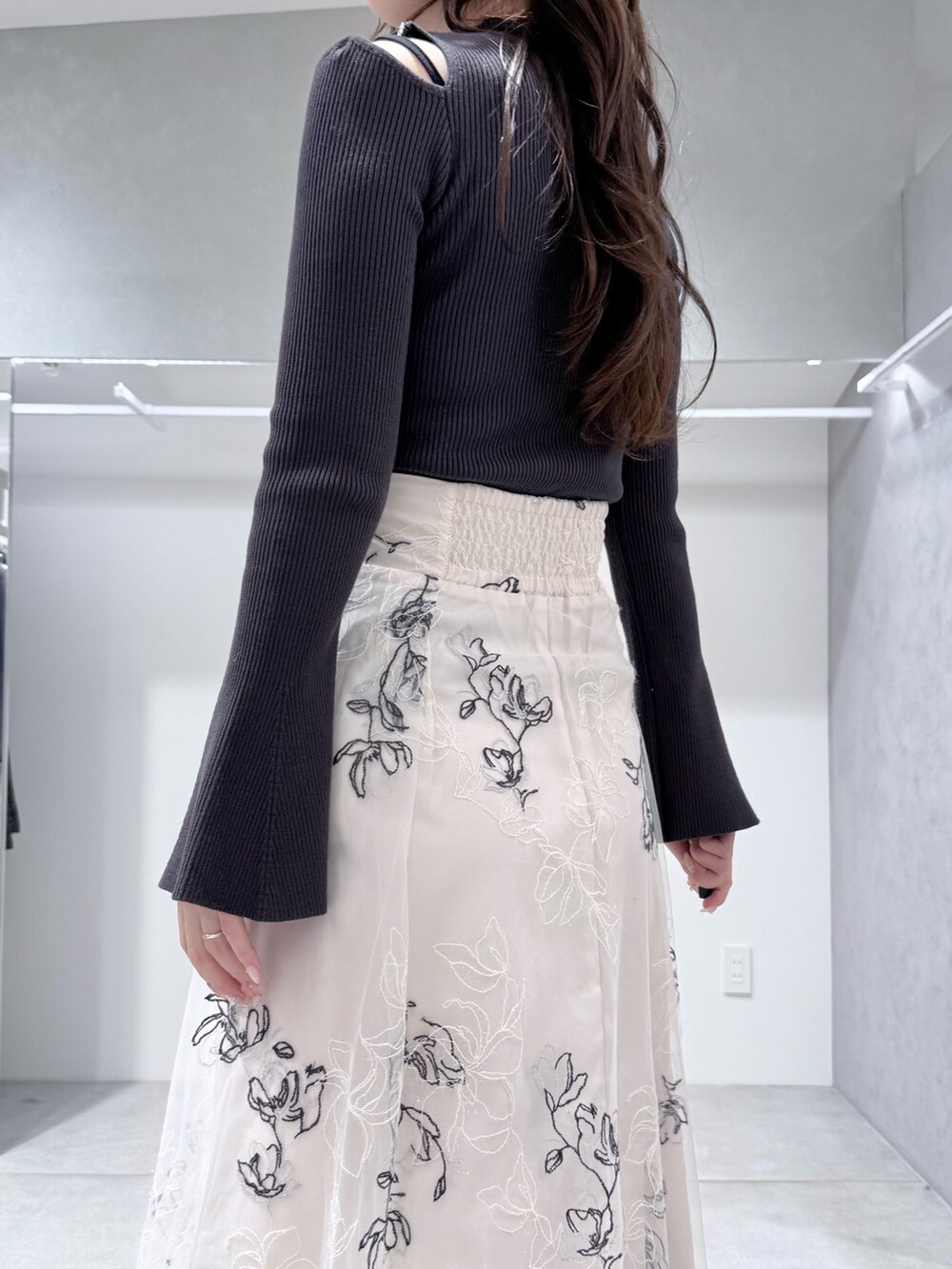 グレー系のニット/セーター、ブラック系のブーツ、ホワイト系のスカートを着用したレディースの冬コーディネートの6枚目の写真