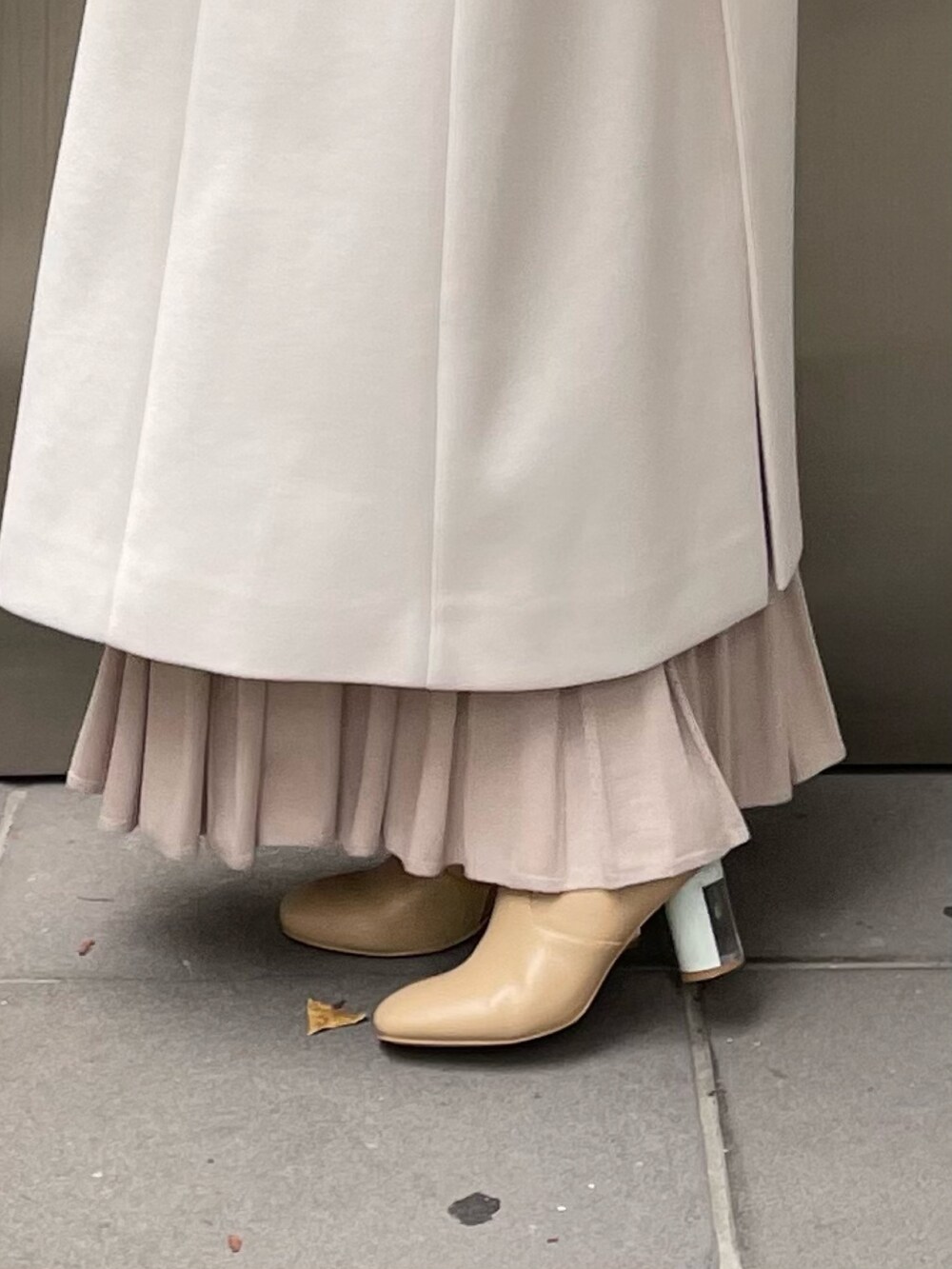 ホワイト系のステンカラーコート、ベージュ系のワンピース、ベージュ系のブーツを着用したレディースの秋コーディネートの10枚目の写真