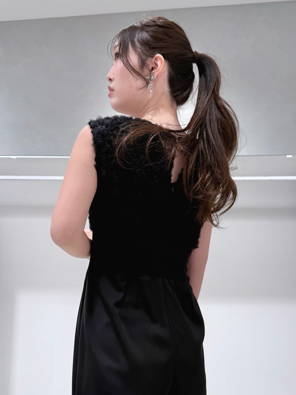 ブラック系のドレス、ゴールド系のショルダーバッグ、シルバー系のパンプスを着用したレディースの冬コーディネートの6枚目の写真