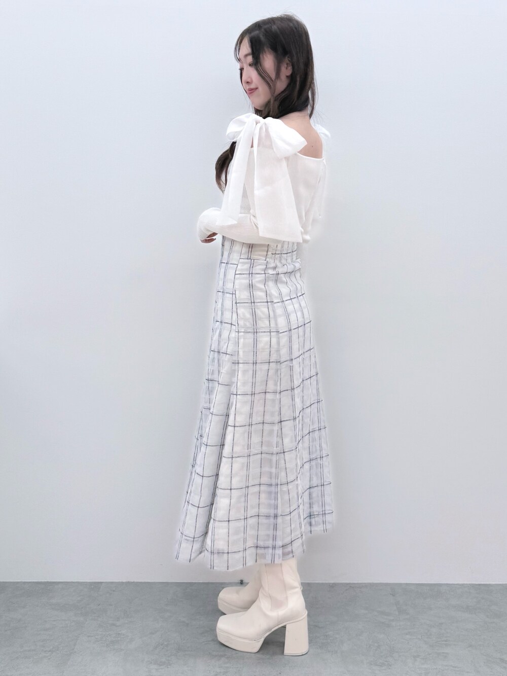 ホワイト系のニット/セーター、ブルー系のスカート、ホワイト系のブーツを着用したレディースの冬コーディネートの3枚目の写真