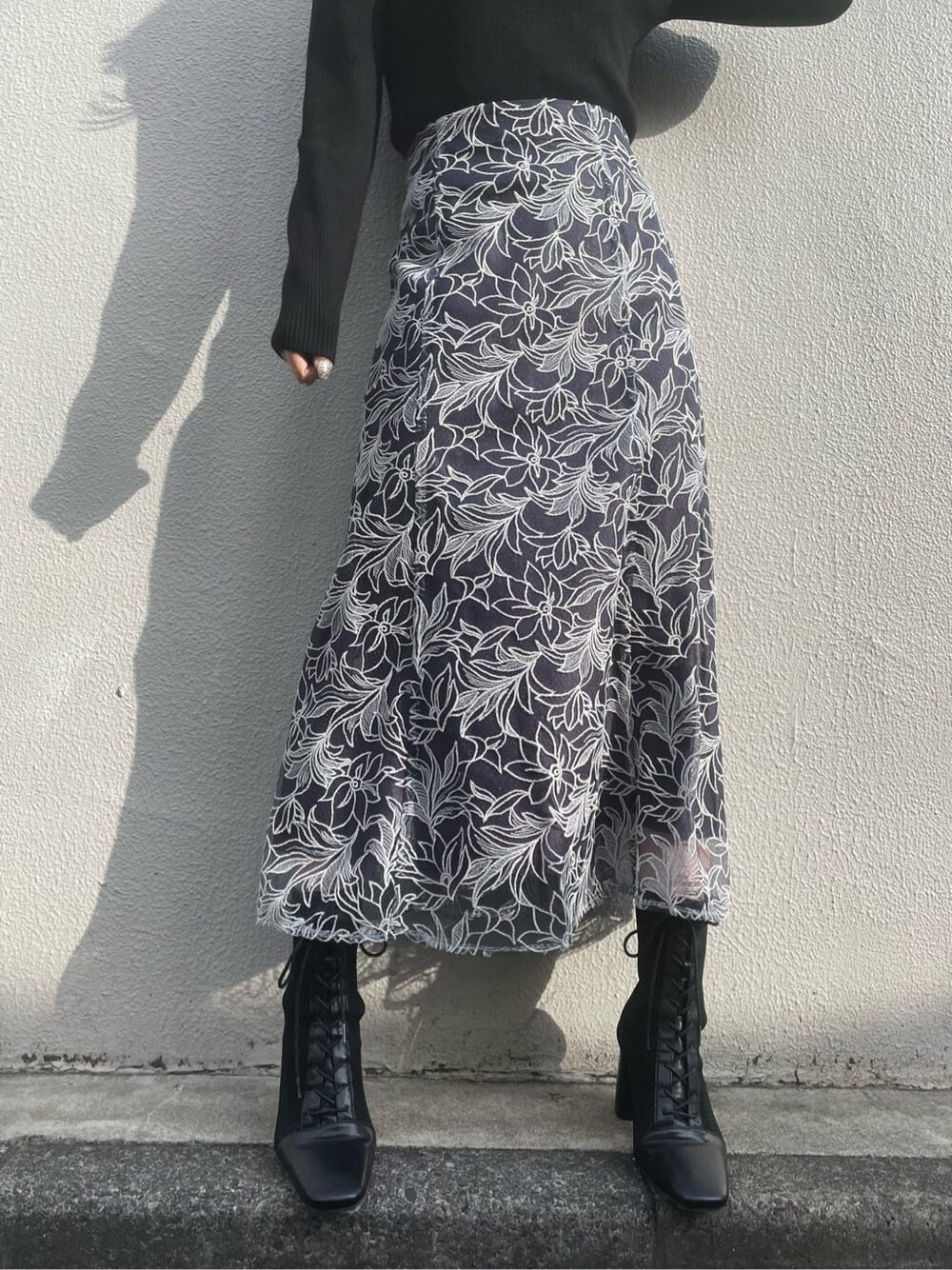 ブラック系のブーツ、ブラック系のニット/セーター、ブルー系のスカートを着用したレディースの冬コーディネートの6枚目の写真