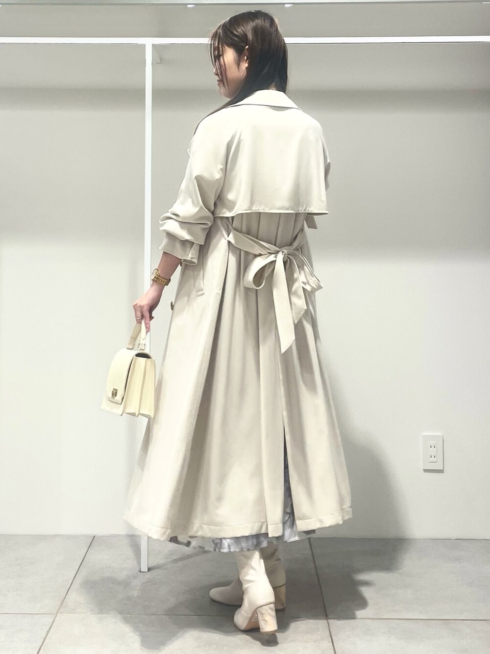 ホワイト系のトレンチコート、ホワイト系のハンドバッグ、パープル系のワンピースを着用したレディースの春コーディネートの3枚目の写真