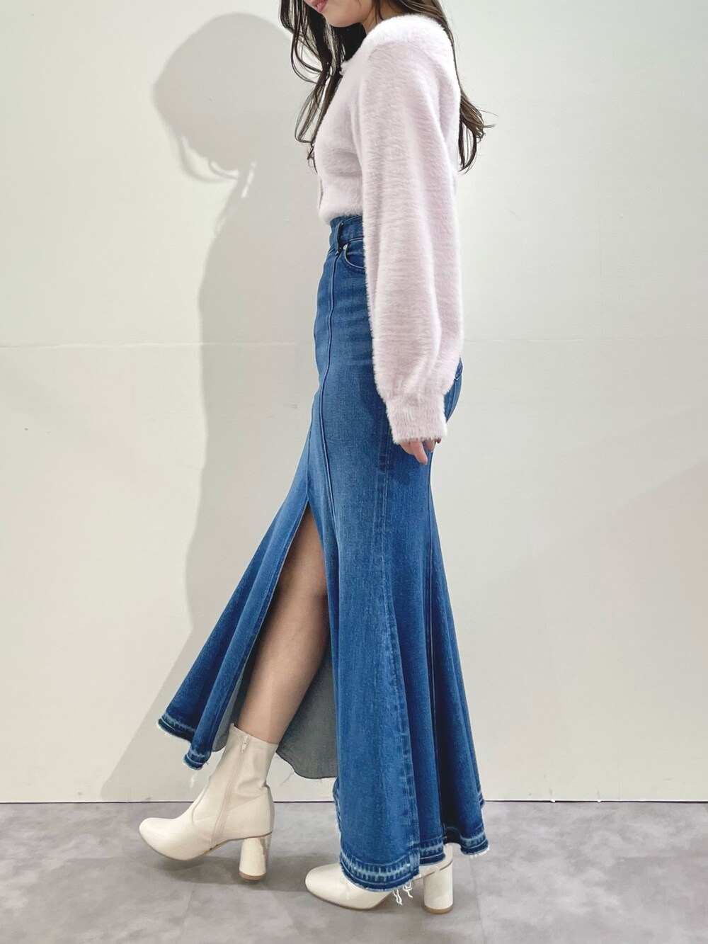 ピンク系のカーディガン/ボレロ、ブルー系のスカート、ホワイト系のブーツを着用したレディースの冬コーディネートの3枚目の写真