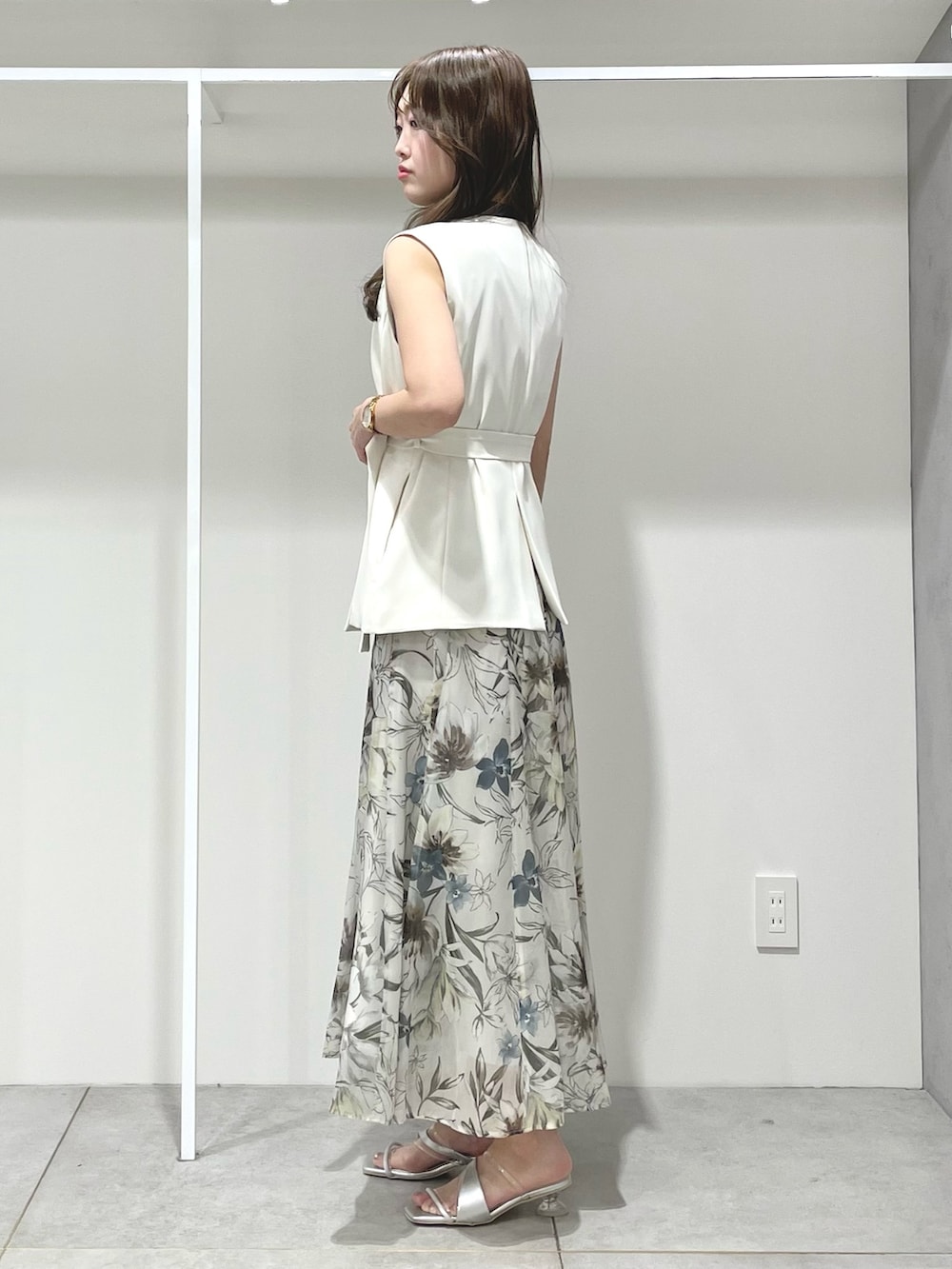 ホワイト系のベスト、グリーン系のスカート、ブルー系のニット/セーターを着用したレディースの春コーディネートの2枚目の写真